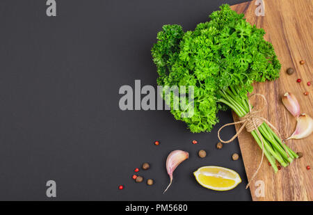 Un bouquet de persil frais bandé avec une corde avec un arc et un mélange d'épices et l'ail sur un tableau noir, vue du dessus Banque D'Images