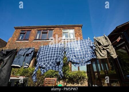 Vérifié shirts et shorts étendus dehors sur un fil a linge séchant sur un jour de vent Banque D'Images