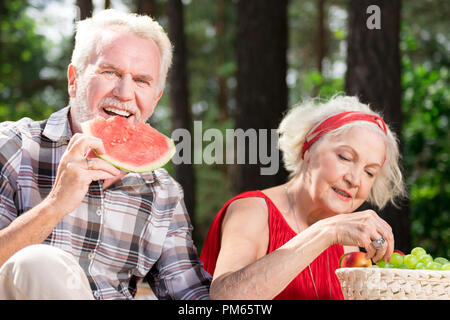 Heureux retraité eating watermelon et sa femme appréciant grapes Banque D'Images