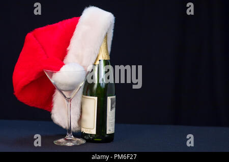 Santa hat reposant sur wine bottle isolé sur fond noir Banque D'Images