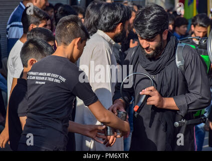 Verre d'eau est donnée à l'chiites du Cachemire en deuil pendant 6e jour d'Ashoura procession à Srinagar le lundi. Musulman chiite commémore Muharram, le premier mois du calendrier lunaire, comme mois de deuil en souvenir du martyre du prophète Muhammad SAWS Islamique petit-fils de l'Imam Hussain (PSL) qui a été martyrisé sur 10e jour de Mouharram en bataille de Karbala en 680 A.D certains il y a 1400 ans. Banque D'Images