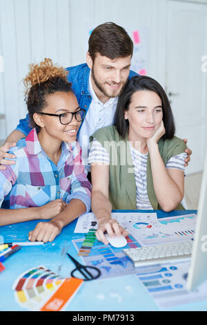 Portrait de trois concepteurs créatifs en utilisant l'ordinateur pour la mise en réseau de l'internet tandis que working at desk in office Banque D'Images
