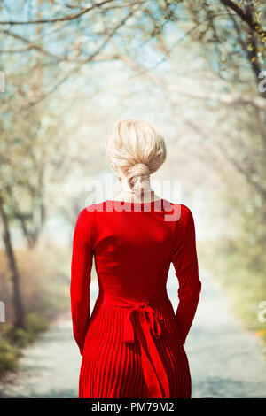 Retro blonde woman standing on country lane au printemps Banque D'Images