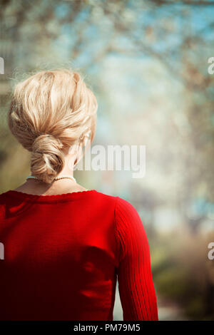 Retro blonde woman standing on country lane au printemps Banque D'Images