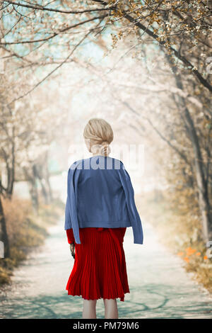 Retro blonde woman standing on country lane au printemps Banque D'Images