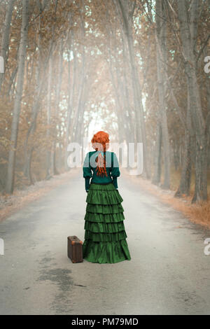 Victorian woman standing on country road avec les arbres d'automne Banque D'Images