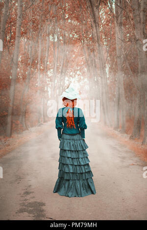 Victorian woman standing on country road avec les arbres d'automne Banque D'Images