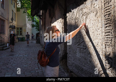 Une femme voyage explorer, vue d'une femme voyageur mature touchant une tombe médiévale dans la vieille ville historique (Vanalinn) de Tallinn, Estonie. Banque D'Images