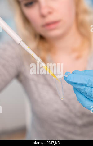 Jeune femme séduisante travailler avec distributeur de PCR dans le laboratoire de génétique Banque D'Images