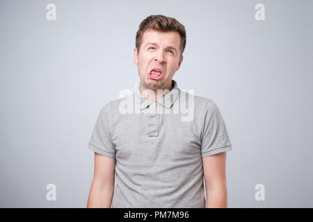 Closeup portrait of funny angry young man sticking bully sa langue à l'appareil photo vous geste, isolé sur fond blanc. Vous êtes dégueulasse concep Banque D'Images