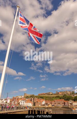 Whitby Harbour et la ville. L'Union flag flotte sur la scène contre un ciel bleu avec des nuages. Banque D'Images