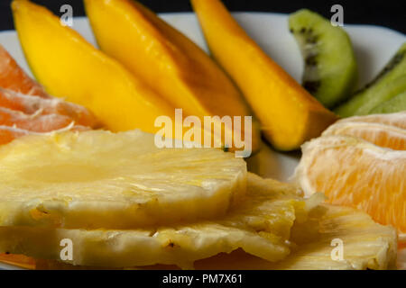 Les fruits tropicaux, kiwi, mangue, ananas, orange et mandarine les tranches d'orange mis sur plaque blanche. Close up, macro photo. Banque D'Images