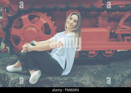 Une jeune femme élégante, habillée en jeans déchirés et chemise blanche posant sur un fond coloré. Visiter le vieux musée des transports. Une femme Banque D'Images