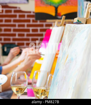 Beaucoup de femmes d'âges différents s'appuyant sur toiles avec des pinceaux et de boire du champagne au cours de maître dans l'art studio, mains seulement Banque D'Images