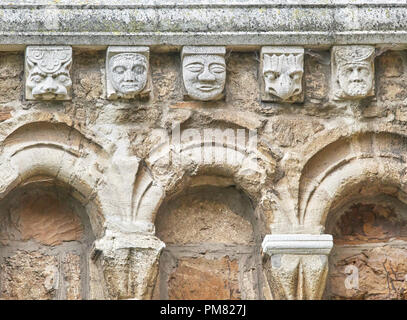 Arches et grotesque sculptures sur pierre sur un mur extérieur de la douzième siècle église normande de Saint Pierre, un bâtiment classé grade 1, dans la ville de Aucun Banque D'Images