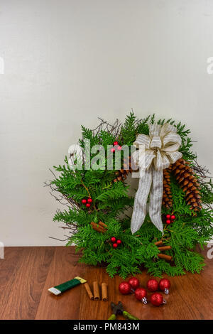 Une couronne de Noël avec des pommes de pin, des bâtons de cannelle, et les grappes de fruits rouges en attente de plus de décorations Banque D'Images