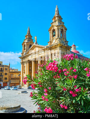 La façade néoclassique de l'église paroissiale St Publius de fleurs de rhododendron arbuste sur l'avant-plan, Floriana, Malte. Banque D'Images