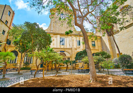 La Valette, MALTE - 17 juin 2018 : Le jardin ombragé dans la cour de Prince Alfred de Grandmaster's Palace avec vue sur la tour de l'horloge derrière la verdure, Banque D'Images