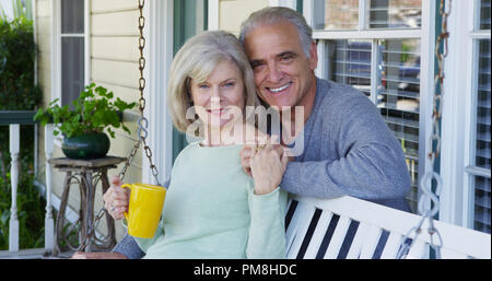 Vieux couple smiling on porch looking at camera Banque D'Images