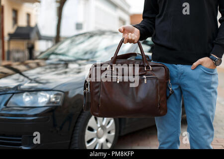 Sac en cuir homme businessman avec près d'une voiture noire Banque D'Images