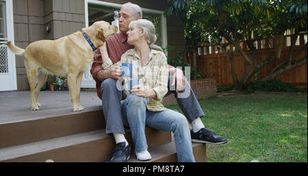 Senior couple having coffee petting dog dans leur cour Banque D'Images