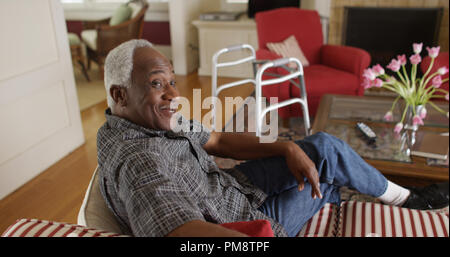 L'homme africain à la retraite assoupli et parler sur son canapé Banque D'Images