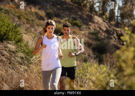 Jeune couple sain d'exécution sur sentier de montagne au matin. Young man and woman jogging le chemin du pays. Banque D'Images