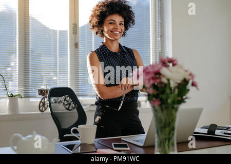 Business Woman debout à côté de son bureau en bureau. Certain femme africaine avec les bras croisés portant tenue décontractée à son lieu de travail. Banque D'Images