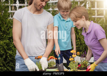 Les jardiniers de la famille avec kid planter des fleurs dans des pots avec de la terre dans la région de farm Banque D'Images