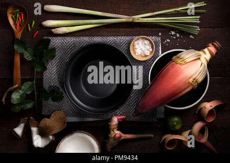 Ingrédients de cuisson des aliments thaïlandais avec crayons, noix de coco, la citronnelle, le piment, sel, citron, citron vert feuille, cuillère en bois et le bol sur planche de bois background Banque D'Images