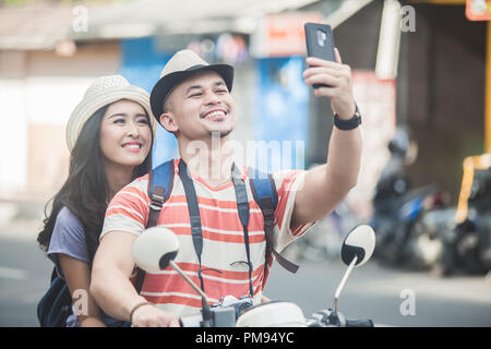 Deux jeunes backpackers en tenant vos autoportraits à l'aide de mobiles configuration camera w Banque D'Images