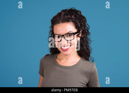 Cheerful woman en tenue décontractée et à rayures smiling at camera sur fond bleu Banque D'Images