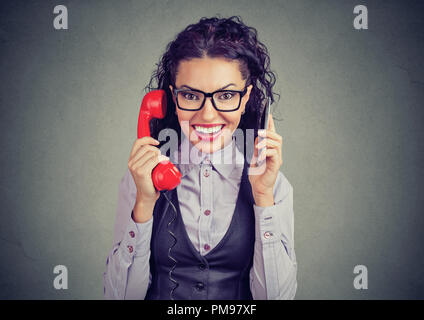 Cheerful curly Woman talking on smartphone moderne et vintage téléphone rouge smiling at camera Banque D'Images