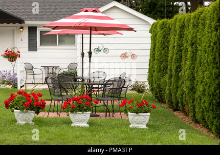 Parapluie blanc et rouge sur l'ensemble de patio en fer forgé, à l'extérieur d'un Bed and Breakfast Inn, sur l'île Mackinac, Michigan. Dans le Midwest des États-Unis. Banque D'Images