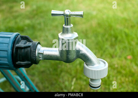 Un robinet d'eau avec tuyau de jardin en plastique gros plan sur l'adaptateur jardin fond d'herbe verte Banque D'Images