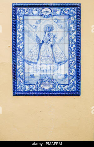 Azulejos (carreaux bleu carreaux) représentant une sainte mère et son bébé méprisé par des anges, ensemble dans un mur jaune citron dans une rue d'Obidos Banque D'Images