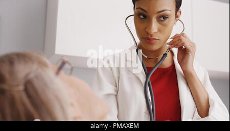 Belle femme médecin de vérifier les signes vitaux du patient with stethoscope Banque D'Images