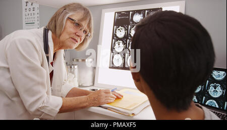 Senior female doctor l'examen des résultats x-ray with patient Banque D'Images