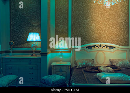 Le plein d'un lit double, avec un flacon de couvrir avec des oreillers avec tables et lampes de chevet avec un lustre en cristal Banque D'Images