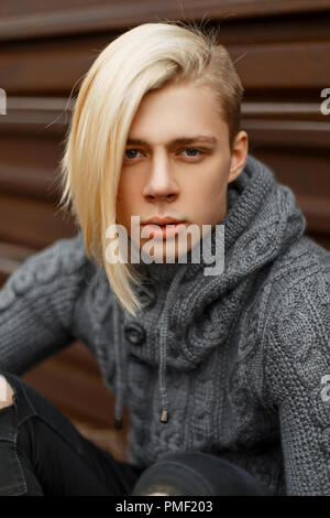 Portrait d'un bel homme à la mode avec une blonde hairstyle dans vintage chandail tricoté gris sur la rue Banque D'Images