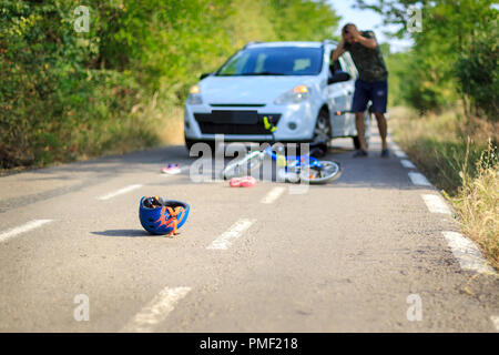 Accident de voiture avec des objets épars et casque de vélo sur route Banque D'Images