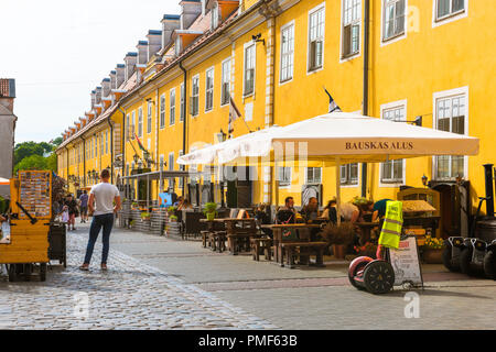 Voir des gens à des tables de terrasse de café à côté de Jacob's Barracks à Tornu Iela, une rue historique dans le centre médiéval de la vieille ville de Riga, Lettonie. Banque D'Images