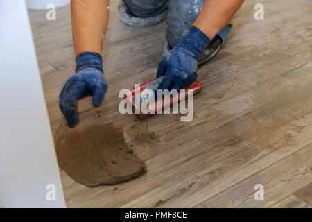 Technicien de la main le travail sur la couleur gris de nouveau sur coulis de ciment gris carreaux pour l'étape finale pour le plancher Banque D'Images