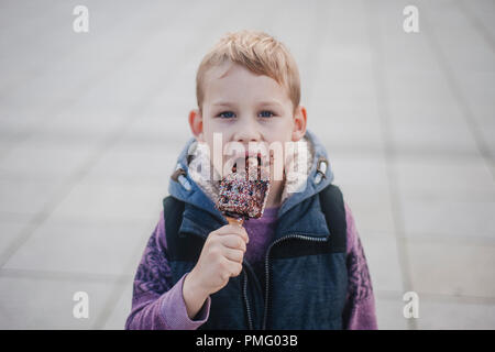 Jeune garçon de manger des gaufres pour le petit déjeuner, tout en regardant vers le haut, dans l'objectif de l'appareil. Gaufres Belges Banque D'Images