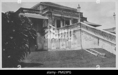 Photographie en noir et blanc sur papier cartonné, avec une image d'un palais en pierre, ou en béton, peut-être une maison privée, tourné à partir d'un angle faible, en vue de trois-quarts, avec portes en bois arqué au niveau du sol, un grand escalier menant au premier étage, piliers de façon ouverte, salon, véranda et une grande terrasse sur le toit, probablement perçus comme un souvenir touristique lors d'un voyage en Asie du Sud (Inde), 1910 probablement. () Banque D'Images