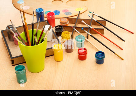 Palette en bois avec jeu de dessins portant sur les peintures et les pinceaux avec la coupe sur la table Banque D'Images