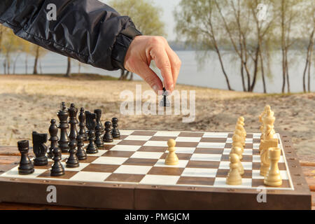 Main hollding mâle est un pion de la deuxième se déplacer dans un jeu d'échecs profondeur de champ à l'accent sur les joueurs part Banque D'Images