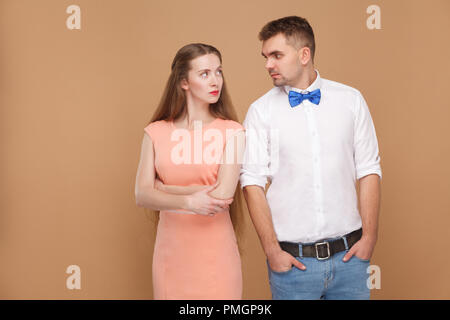 Portrait de bel homme en chemise blanche et bleu arc et belle blonde femme en robe rose à la recherche d'un l'autre avec sérieux. Piscine studio s Banque D'Images