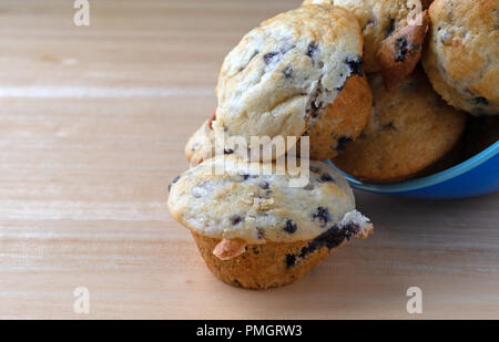 Fermer voir de petits muffins aux bleuets un bol bleu sur le côté sur une table en bois. Banque D'Images