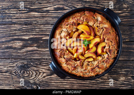 Peach Cobbler fait maison, avec du remplissage dans un plat noir, à base de pêches d'été, vue horizontale à partir de ci-dessus, mise à plat Banque D'Images